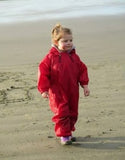 girl walking on beach wearing Muddy Buddy waterproof coveralls in red