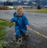 Child splashing in a puddle wearing Muddy Buddy waterproof coveralls in blue